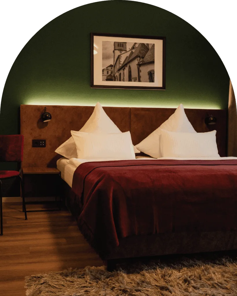 Das-Muehlentor-Restaurant-Hotel-Bad-Kreuznach-Zimmer-Doppelbett-vor-gruener-Wand-mit-dunkelroter-Tagesdecke